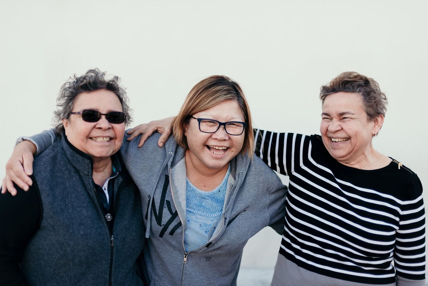 Three women laughing together, arms around each other