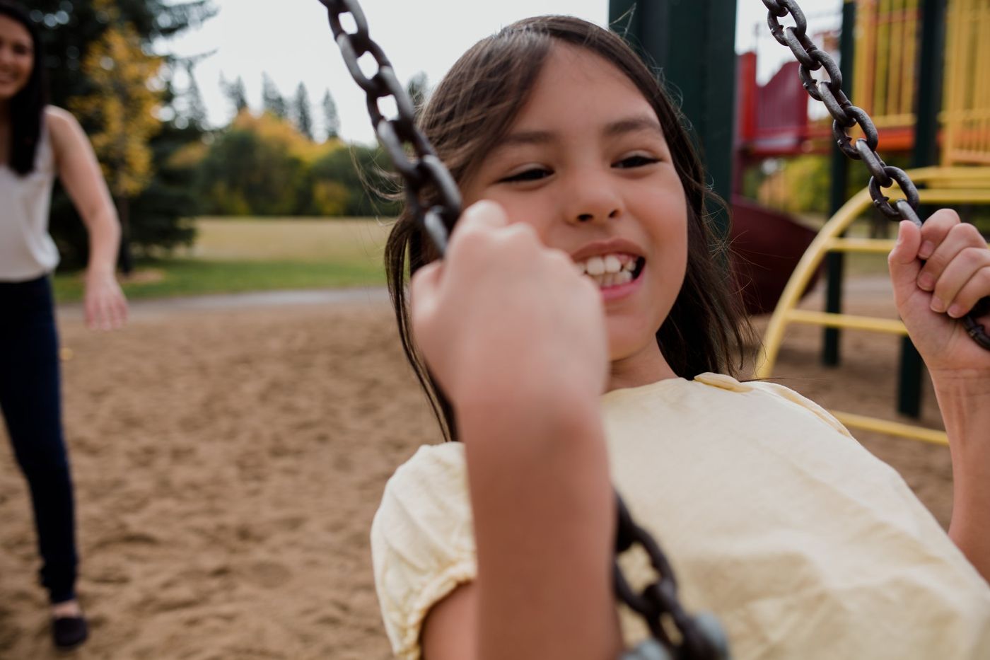 A girl laughing on a playground swing