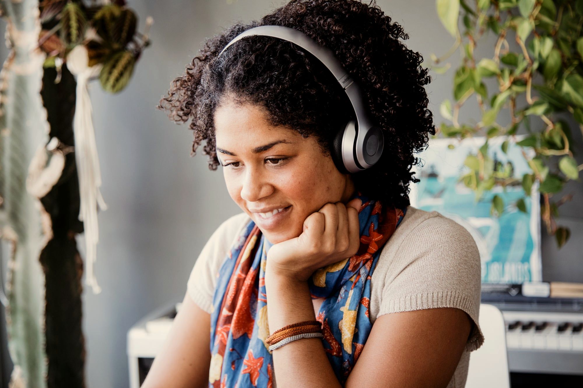 A woman wearing headphones, smiling and relaxed, chin resting on her hand