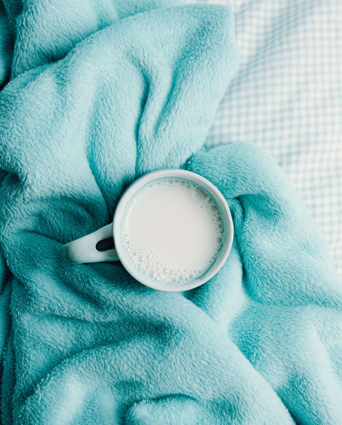 A soft blue blanket and a cup of warm milk