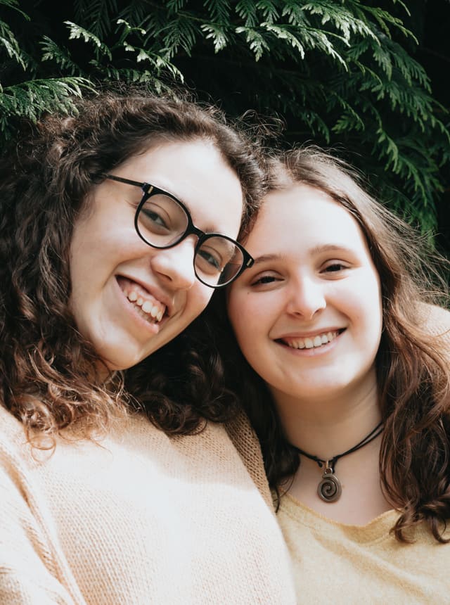 Two teenage girls smiling, arm in arm