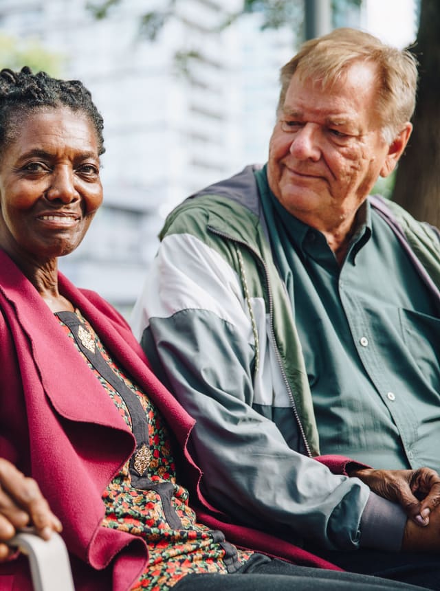 An older couple sitting together on a park bench