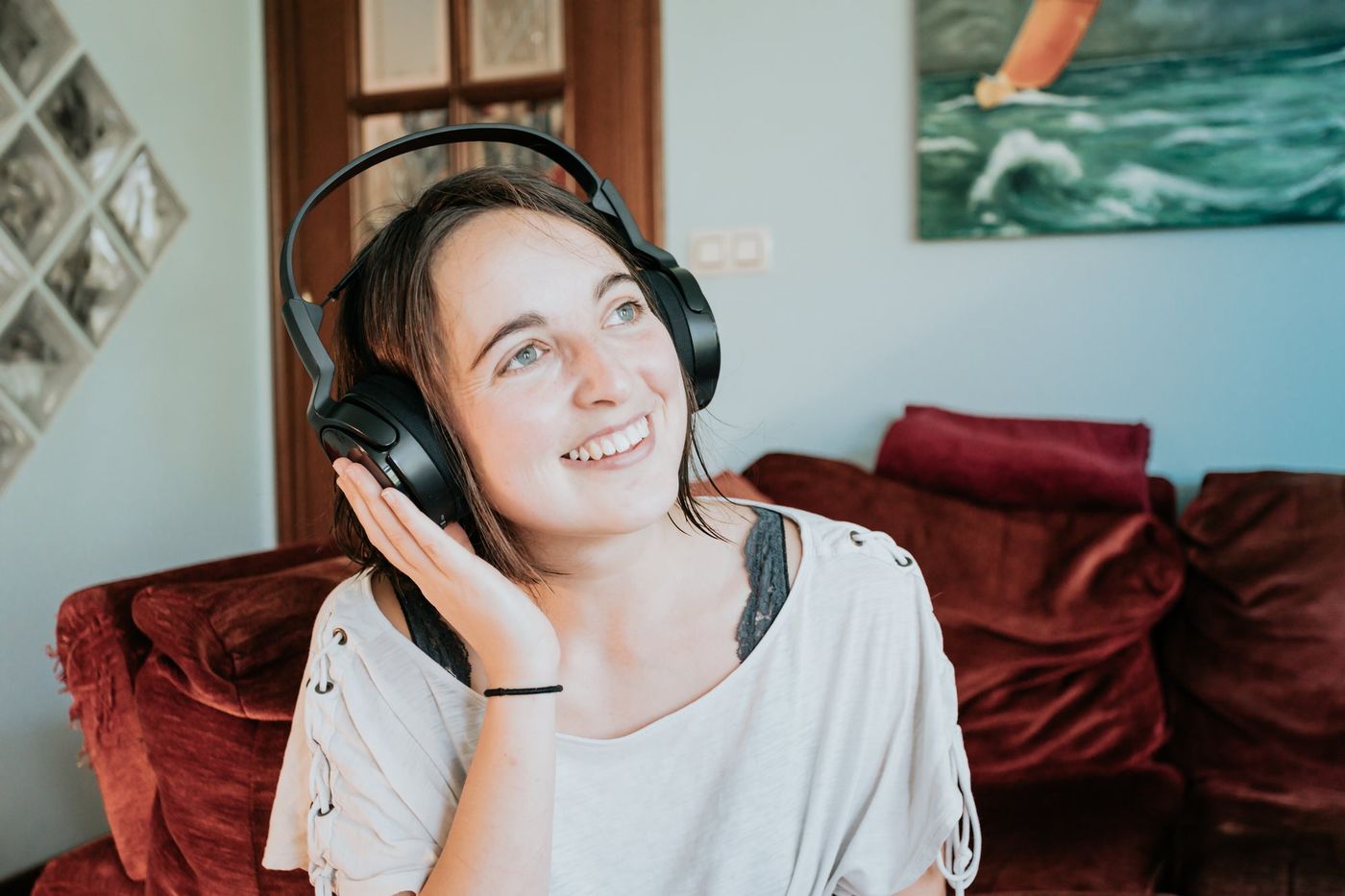 A woman smiling with headphones on, relaxed on a sofa