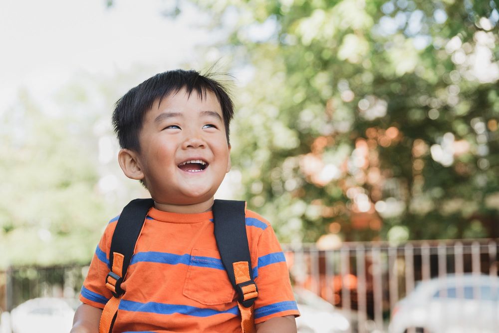 A young boy with a backpack laughing