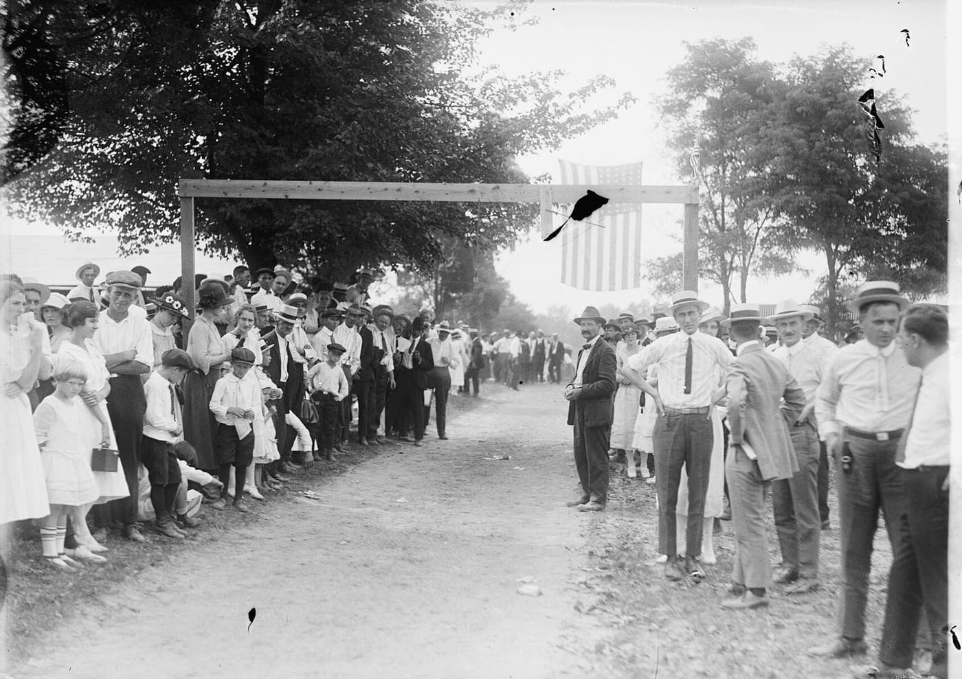 A crowd lines a dirt road in Vienna for a Fourth of July celebration, early 1900s.