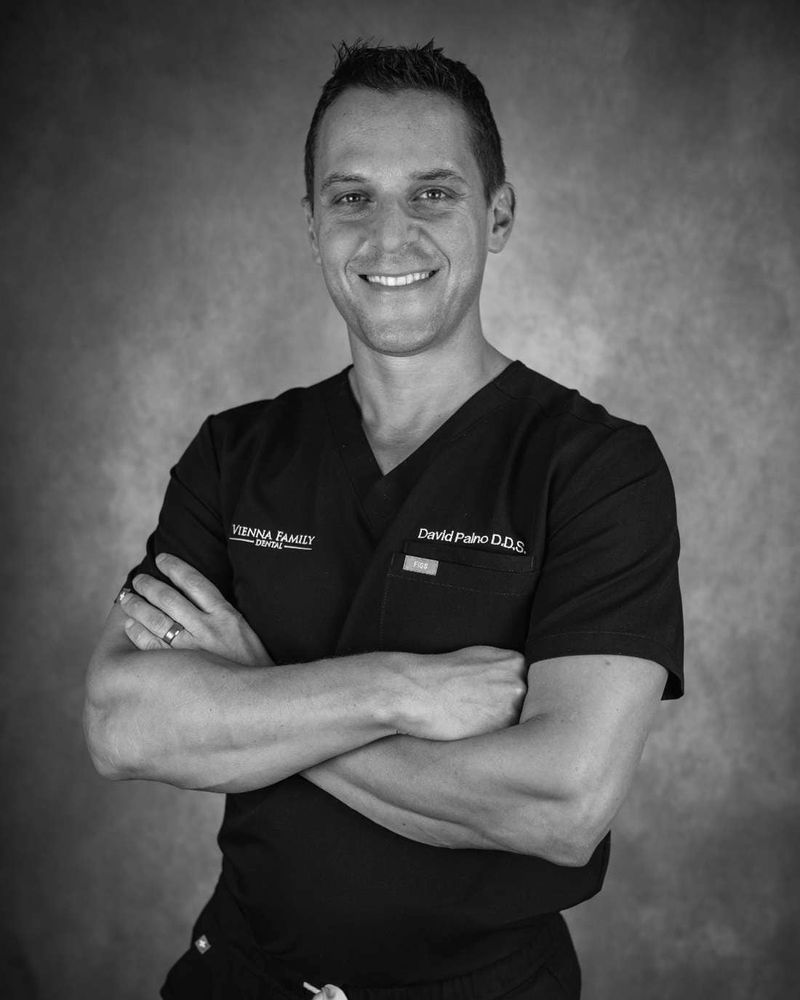 Dr. David Paino, arms folded, in black scrubs.
