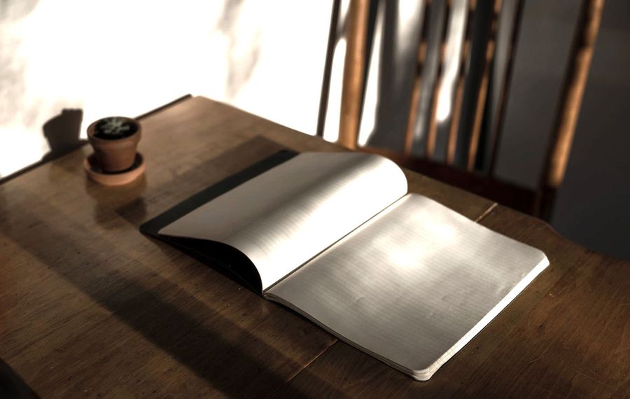A notebook lying open on a wooden table in low light