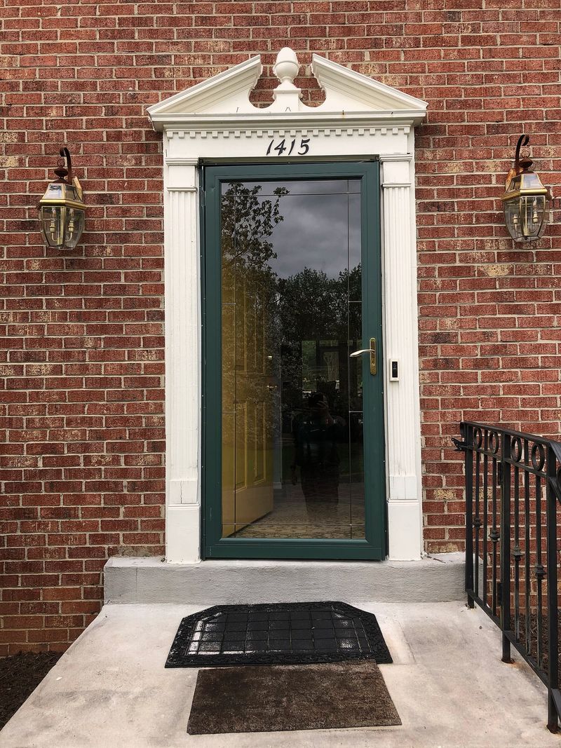 A green front door with brass lamps in a brick house in Vienna